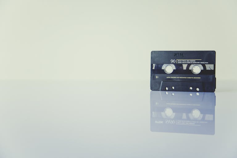 Retro cassette tape on a reflective surface, evoking nostalgia and vintage music vibes.
