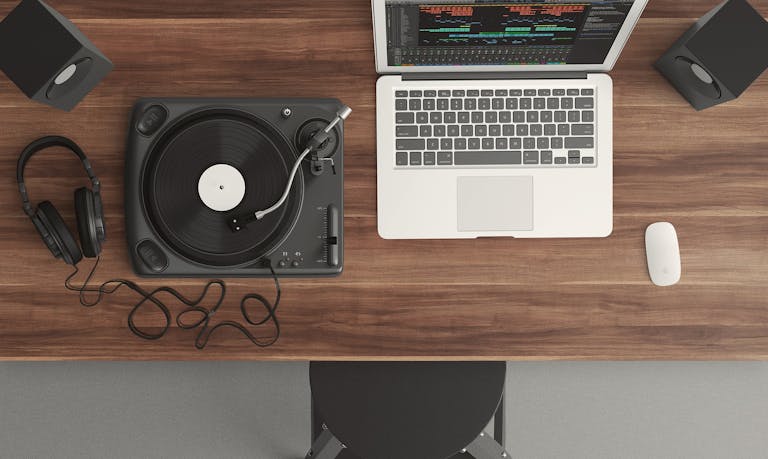 Top view of a music production desk with a laptop and turntable setup for modern audio production.