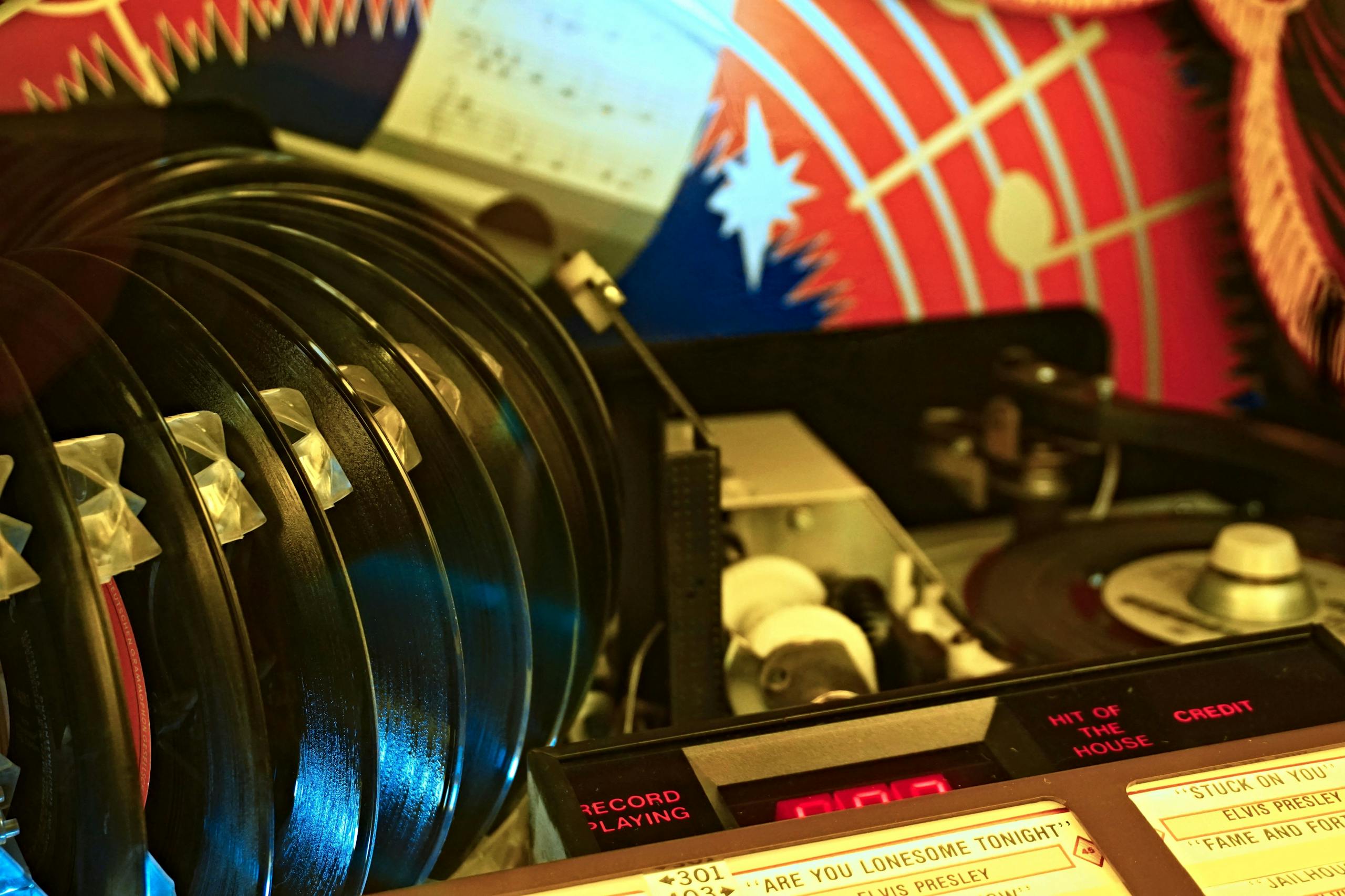 Close-up of a retro jukebox featuring vinyl records and classic hits playing in a vibrant setting.